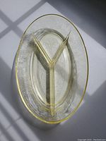 Top view of oval yellow depression glass serving dish showing three compartments and detailed embossed patterns.