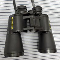 Top view of black Bushnell Powerview 10x50 binoculars with yellow Bushnell logo on each eyepiece housing.