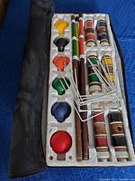 Top view of croquet set components in foam tray with carrying case on left