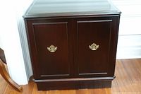 Front view showing dark brown double door cabinet with gold-tone handles.