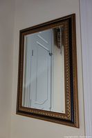Front view of rectangular wall mirror mounted on white wall, showing reflective surface and decorative frame.