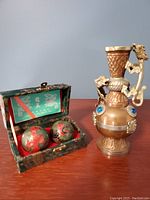 Full view of mixed metal decorative vase next to the open box containing two Chinese health balls with dragon motifs.