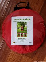 Red circular carrying case with Insect-a-hide label showing product image and description.