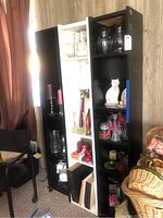 Three tall storage cabinets placed side by side with various decorative glassware and candles inside the shelves.