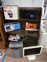 Electronics including monitor, shredder, router, camera, DVD players on wooden shelving