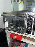View of the entire Farberware toaster oven showing the front glass door, handle, and control knobs on the right side.
