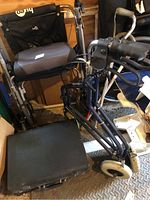 Photo showing rollator walker with seat, backrest and storage pouch, along with two quad canes and a black briefcase on floor