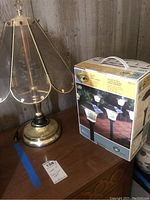 Brass table lamp next to boxed Hampton Bay 6-pack solar path lights on wooden surface