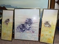 Three framed prints featuring kittens in outdoor settings with soft colors, gold colored frames.