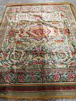 Full view of the colorful bedspread showing the central medallion and floral patterns with various shades of red, green, and cream.