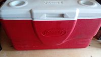 Front view of the large Coleman cooler with red body and white lid, Coleman logo visible on front and lid.