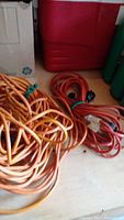 Multiple coiled extension cords in orange and red bundles on a surface