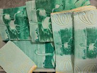 Multiple towels and wash mitts folded showing green flamingo decorative pattern with cream background and yellow decorative border