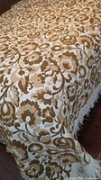 Close-up of the brown and cream floral patterned fabric draped over a bed, showing the texture and design details.
