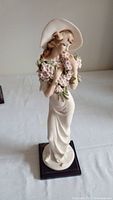 Full view of the Giuseppe Armani porcelain figurine showing the entire figure including dress, hat, flowers, and base.