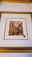 Framed print of Tom Thompson's Autumn Landscape in autumn colors with a gold frame and double matting.