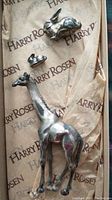 Photo showing two silver rabbits and a giraffe figurine on branded Harry Rosen tissue paper.