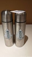 Photo of two stainless steel thermoses side by side showing the WOODS tree logo on the front.