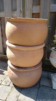 Stack of three terracotta pots with visible wear and chip on rim