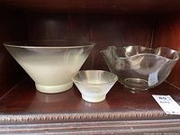 Three bowls on a wooden shelf: two frosted chip and dip bowls with gold rim and one clear glass bowl with scalloped edges.