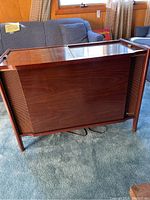 Front view of walnut finish wood veneer Magnavox stereo console with speaker grills on either side and hinged top closed