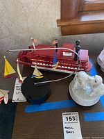 All three music boxes shown together on a wooden surface: tugboat, sailboats mobile, and porcelain dogs.