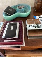 Overview of all smoking accessories on a wooden surface including ashtray, lighter, roller, and holder.