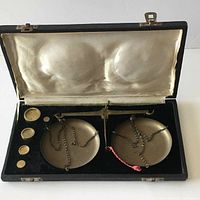 Overall view of the antique balance scale with pans in fitted case lined with satin and felt.