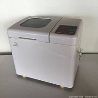 Full side view of white bread maker machine with top lid and control panel to the right side.