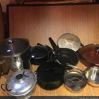 Top view of entire lot showing all cooking pots, pans, steamers and accessories on a wooden surface