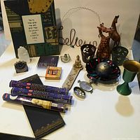 View of entire lot with quartz crystal, wooden giraffes, incense packs, Buddha figurine, candles, decorative bowls, and miscellaneous items.