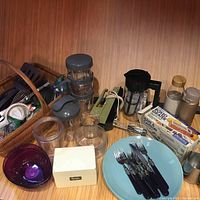 Overall view of kitchenware items including plates, forks, glass containers, and plastic wrap rolls