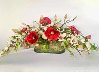 Front view showing full floral arrangement in solid rounded rectangle glass vase with moss inside.