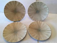 Four round dinner plates with embossed dotted pattern and beige-gray reactive glaze