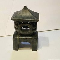 Front facing image of soapstone pagoda carving showing square base, openings in center, and pointed roof tip.