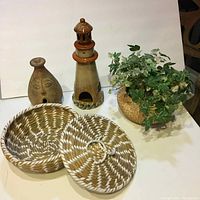 Overview of all items including the woven basket with lid, ceramic vase, lighthouse lantern, and floral arrangement in woven basket.