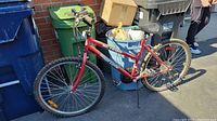Full view of red Supercycle SC 1800 mountain bike leaning against recycling bins, showing frame, wheels and handlebar