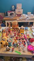 Full view of Disney character figurines arranged on a tabletops including Toy Story characters, Mickey and Minnie Mouse, Winnie the Pooh, and other characters. Some toys are wind-up.