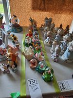 Photo showing 13 Disney snow globes of various characters on a table with some tags visible.