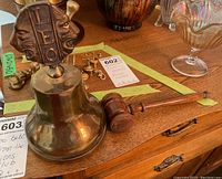 Close-up of brass Leo bell with lion heads on handle next to wooden gavel on wooden table surface