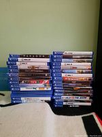 Two stacked columns of PS4 game cases on a blanket