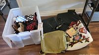 Multiple purses and bags including a clear bin with various purses, a beige textured backpack, black leather purse, and colorful owl-themed tote bag with tags.