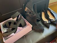 Photo showing all three pairs of shoes together: black chunky platform heels in box, black faux suede ankle boots with zipper, black pointed-toe dress wedges with bow detail.