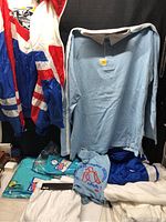 Full view of various tennis wear pieces including jackets, shirts, and shorts laid out on a surface