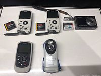 Five cameras: two Kodak cameras with batteries and three Sony Cyber-shot cameras.