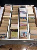 Photo showing multiple bundles of baseball cards organized neatly in a divided box, with various player's backs visible.