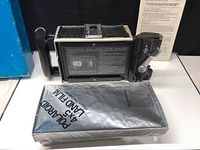 Camera body opened with film holder, sealed film pack and instruction sheet on display