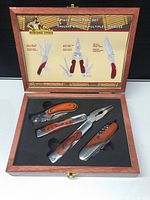 Open wooden case showing the three multi tools with wood handles fitted into foam cutouts. The inside lid displays the Heritage Tools branding and labels for each tool.