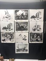 Lot of 10 black and white Walt Disney photos from the movie Pinocchio pinned on a black board.