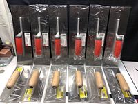 Lot of 12 new professional trowels including 6 with plastic handles and notched stainless steel blades, and 6 with wooden handles and smooth stainless steel blades